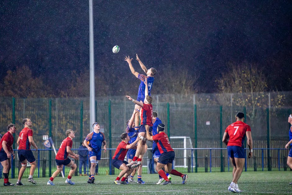 Rugby players compete in a lineout during a match in England, captured on a rainy night.