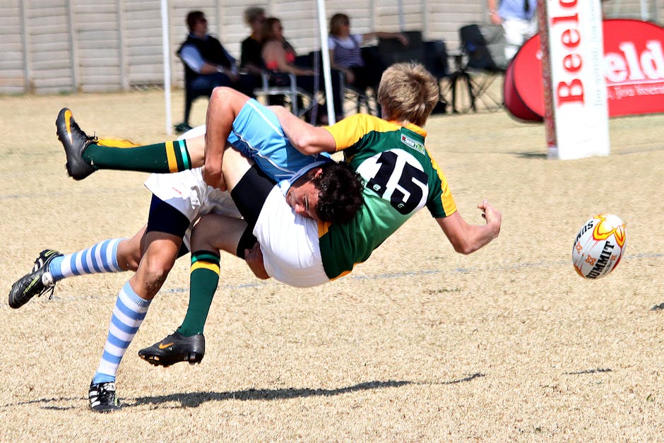 Two rugby players collide mid-air in an action-packed outdoor rugby match.