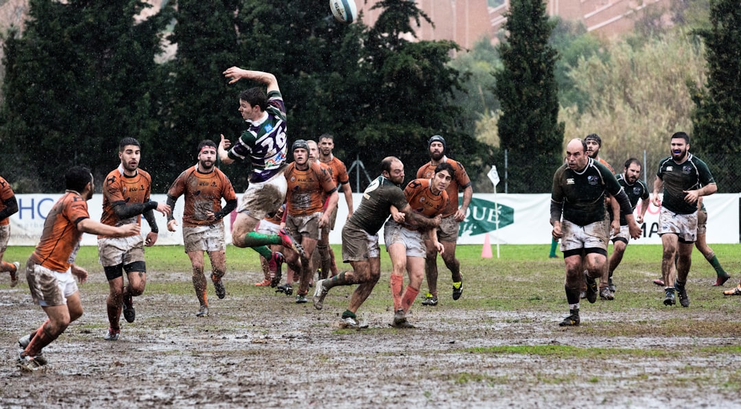 person wearing black jersey jumps across people wearing orange jerseys