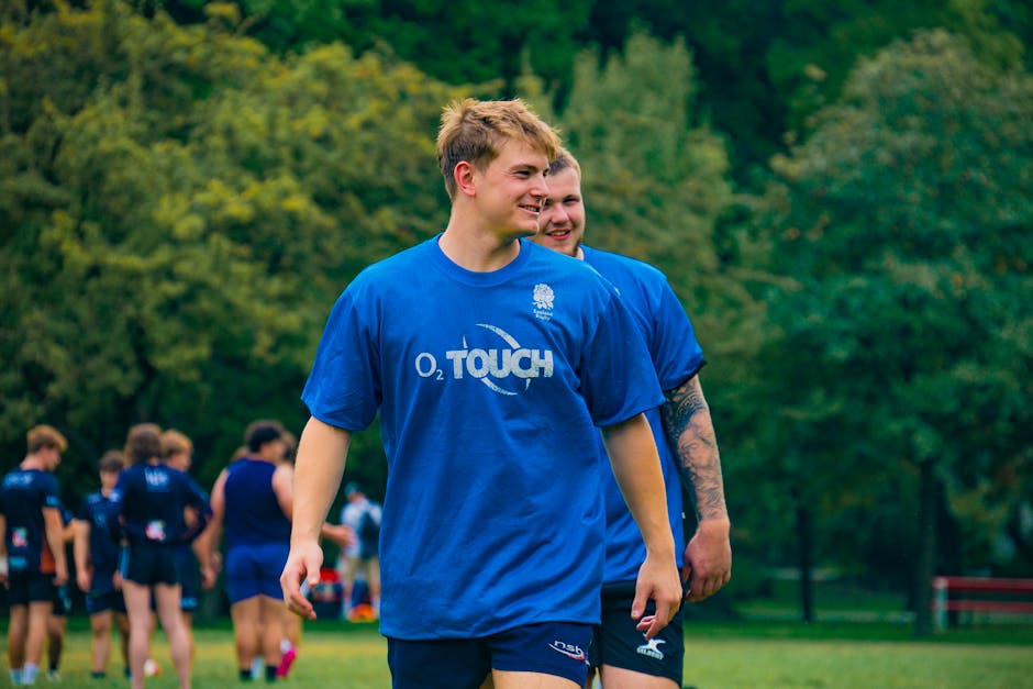 Young men in blue jerseys participating in rugby practice outdoors in a lush green park during the day.
