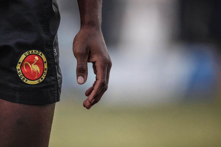 Zoomed-in view of Uganda Rugby Union shorts with an adult hand visible.