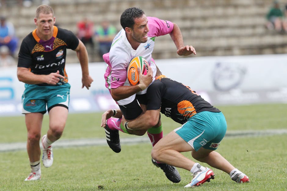Rugby players encounter a powerful tackle during a competitive outdoor match on the field.